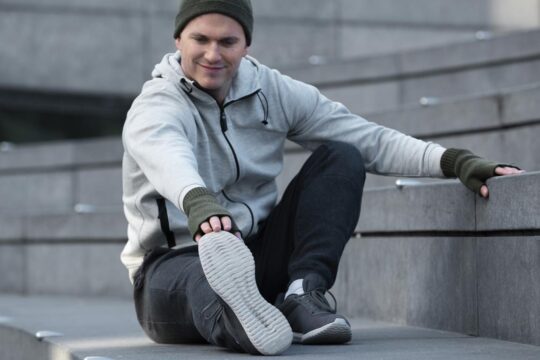 Hombre con un look casual combinando Skechers blancas con vaqueros y una chaqueta deportiva