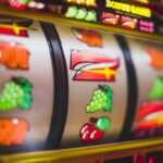Pantalla de ordenador mostrando una slot online con rodillos temáticos y colores vibrantes en un entorno doméstico acogedor.