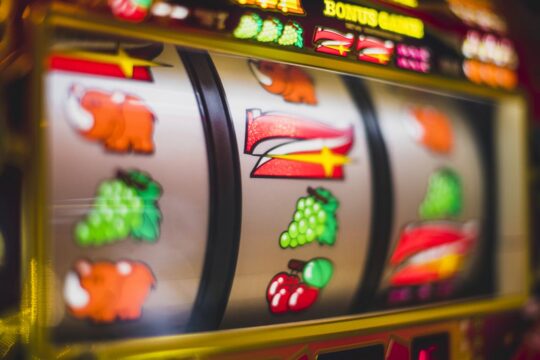 Pantalla de ordenador mostrando una slot online con rodillos temáticos y colores vibrantes en un entorno doméstico acogedor.