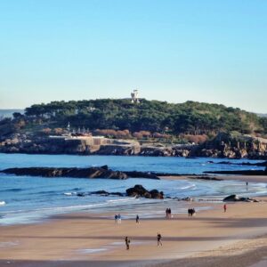 Familia disfrutando de un día soleado en la Playa de San José, con sombrillas y niños jugando en la orilla.